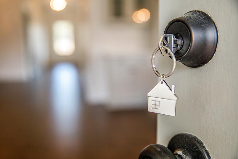 A key with a house keychain in the lock of a front door of a new home.