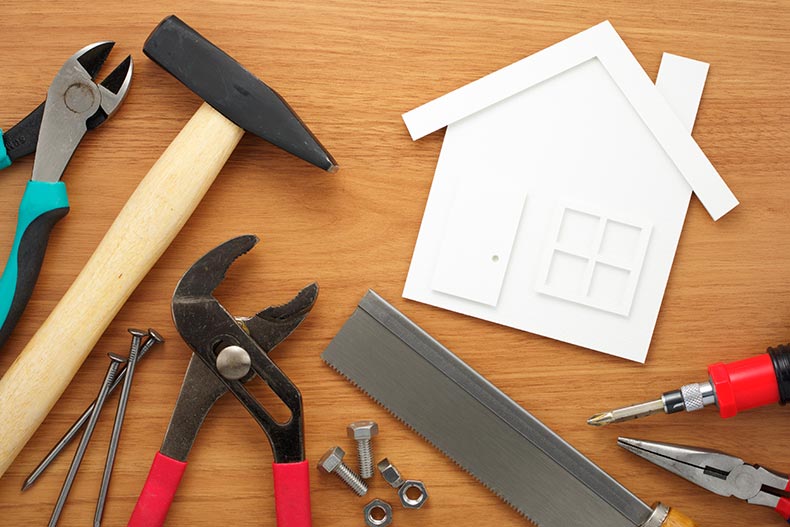 Tools laying around a white cutout of a house.