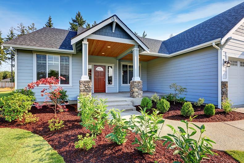 A light blue house with a stone porch and concrete walkway in the Northwest region of the U.S.