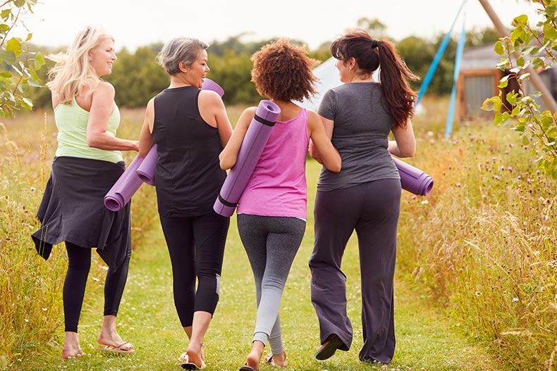 Rear view of a group of mature friends enjoying outdoor yoga in their 55+ community.