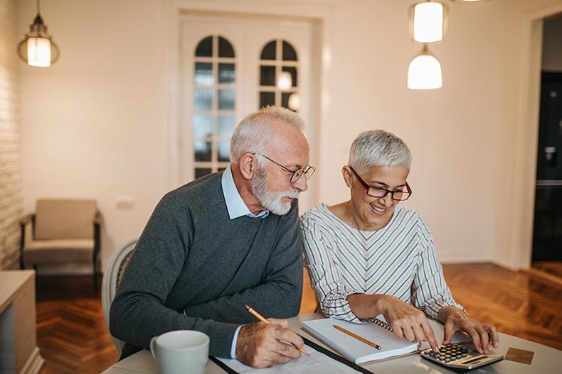 A 55+ couple calculating how much money they'll save by downsizing their house.