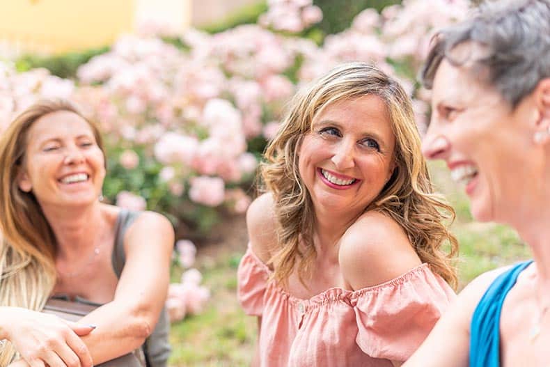 Women talking and laughing while sitting outside in their 55+ community.