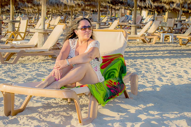 A 55+ woman sitting in a beach chair sunbathing on a sunny day in Puerto Vallarta in Jalisco, Mexico.