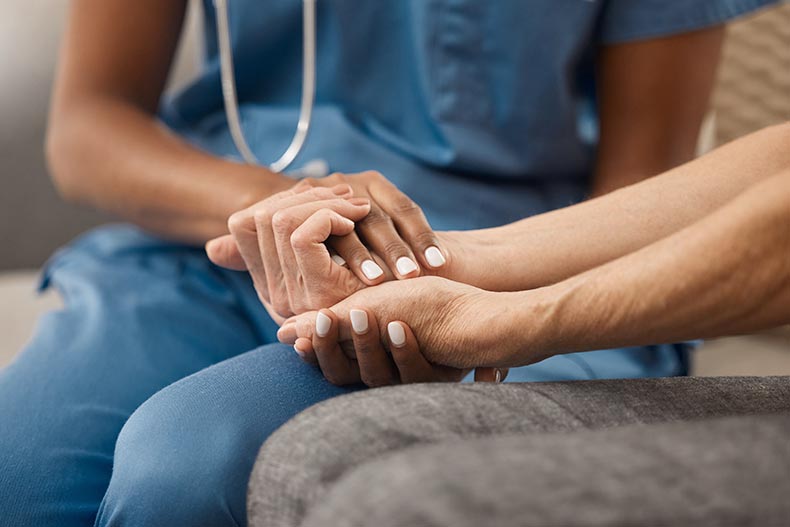 A doctor holding hands with her patient.