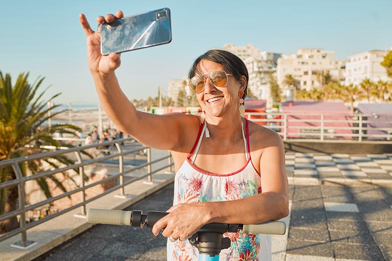 A 55+ woman taking a picture while having fun during her retirement in Mexico.