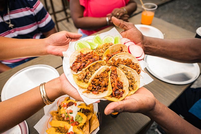 Friends sharing a plate of tacos at a restaurant in Mexico.