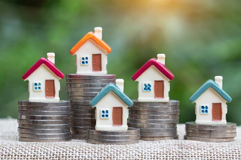 Tiny, colorful model homes on stacks of coins.