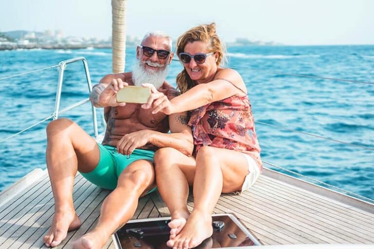 A senior couple taking a selfie on a sailboat while snowbirding in Mexico.