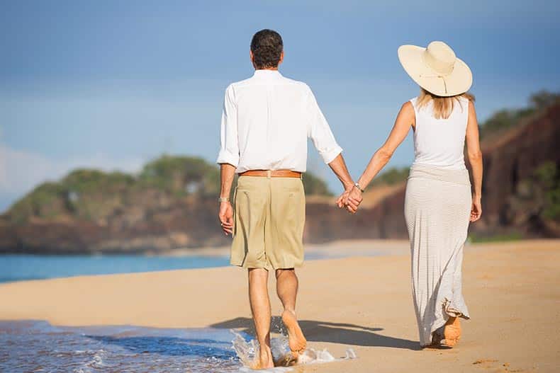 A happy senior couple walking on a beach in Mexico.