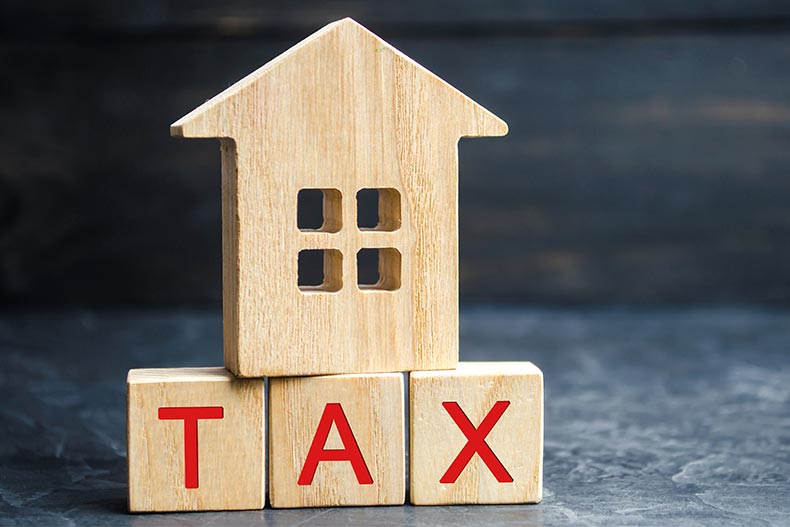 A wood house model on top of blocks spelling "TAX."