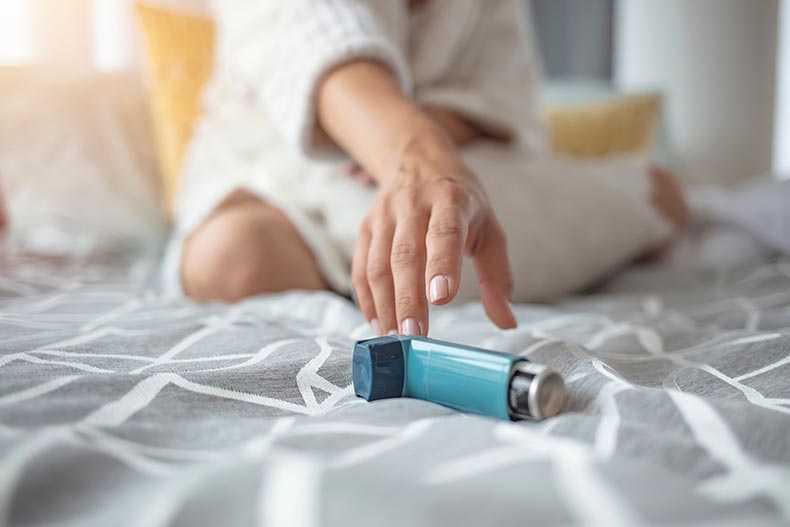 An asthmatic 55+ woman reaching for an inhaler.