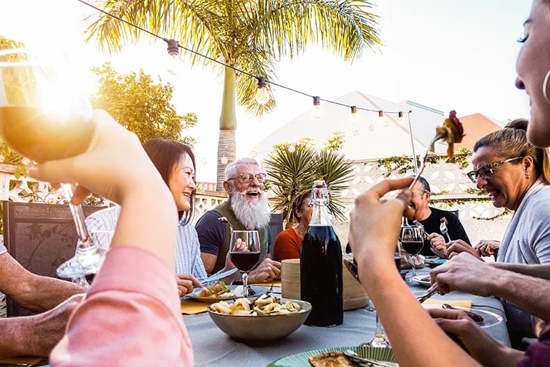 A happy family having dinner outside at sunset.