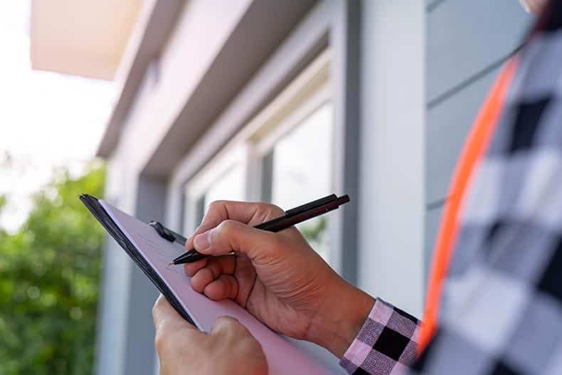 Close up of an inspector checking a house by using checklist.