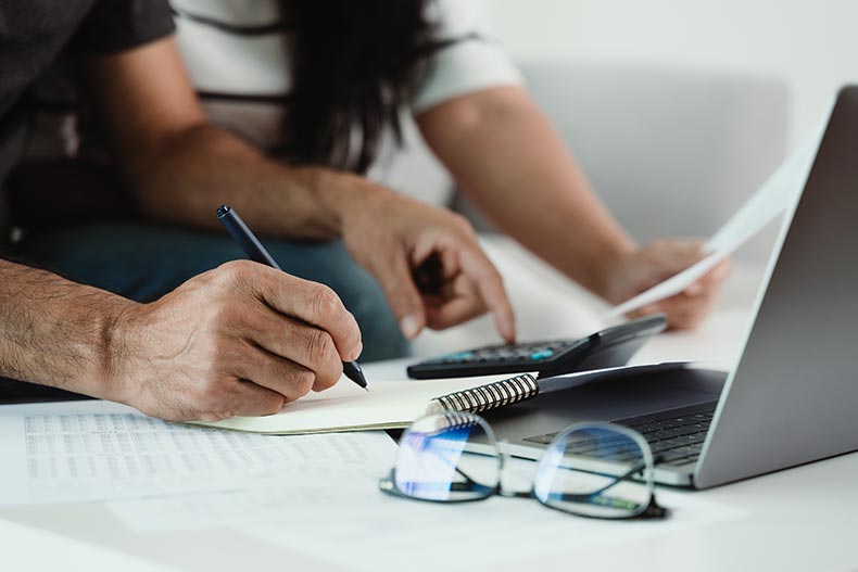 A 55+ man and woman calculating their taxes with a calculator.