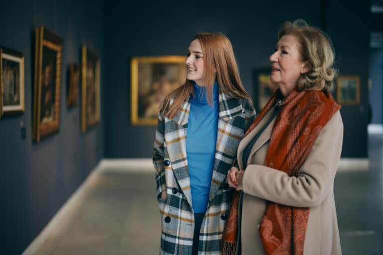 A mature woman explores an art gallery with her granddaughter in one of her favorite retirement cities.