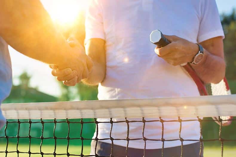 A 55+ tennis player shaking hands on the tennis court.