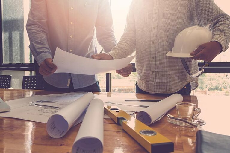 Blueprints and tools on a desk as home builders plan a construction site.