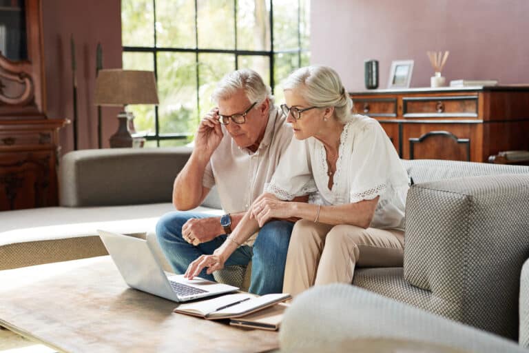 Older couple sits on couching doing their taxes in a no income tax state.