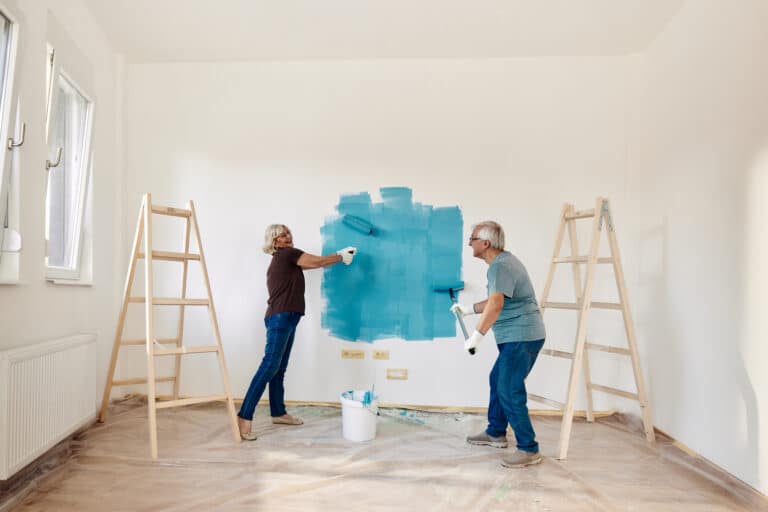 A 55+ couple decorates on a budget by painting an accent wall.