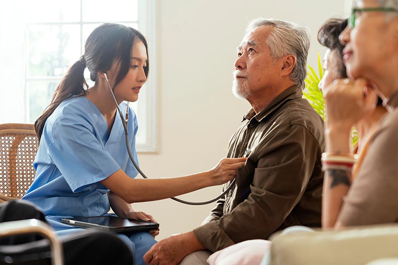 A nurse using a stethoscope during an elderly man's check up.