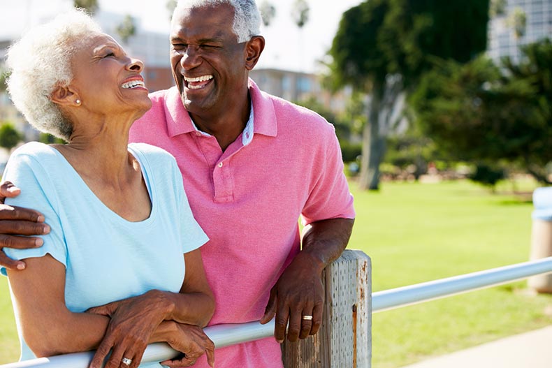 A smiling and laughing 55+ couple enjoying the outdoors near their new home.