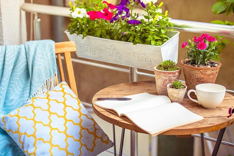 A beautiful terrace or balcony with a small table, a chair, and flowers.