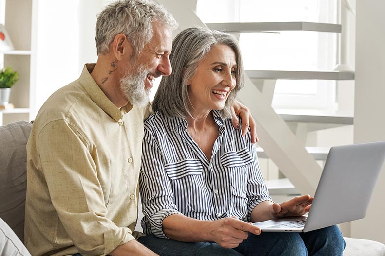 A happy retired couple shopping for a home online.