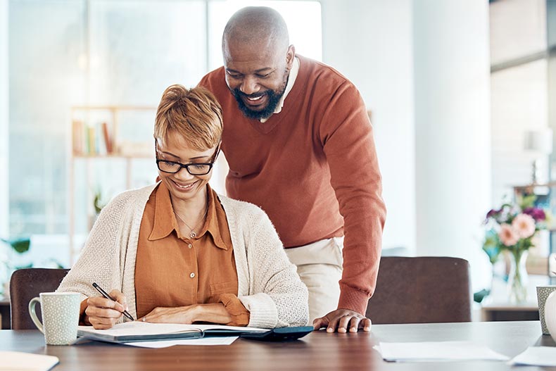 A smiling 55+ couple managing their finances at home.