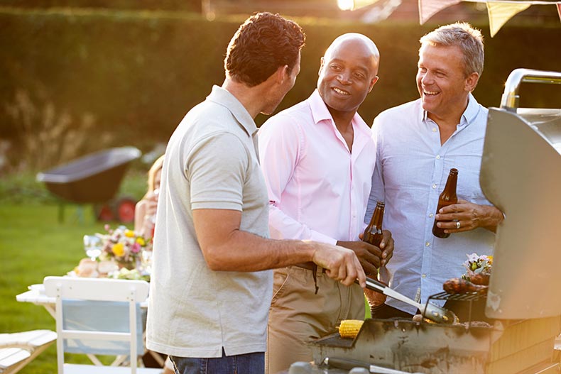 Three 55+ male friends enjoying a summer barbecue.