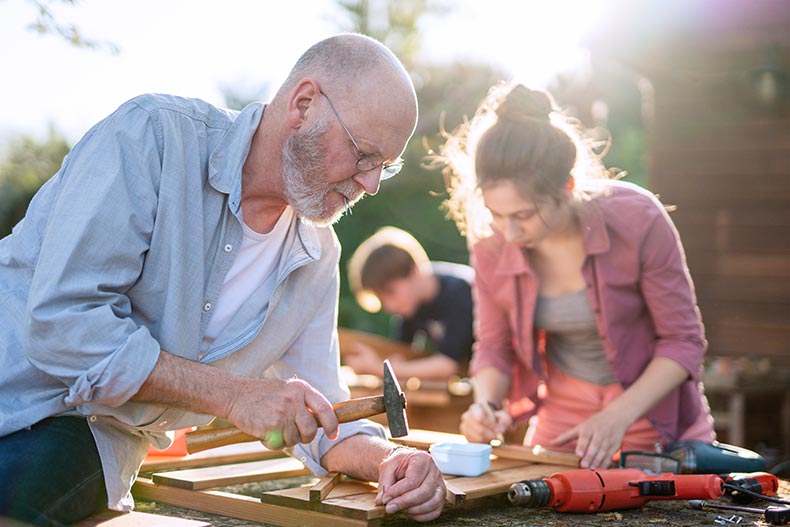 A 55+ man and his family building a DIY project together outdoors.