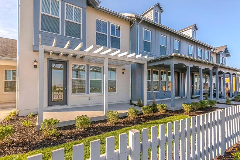 Townhouses with yards and a white fence.