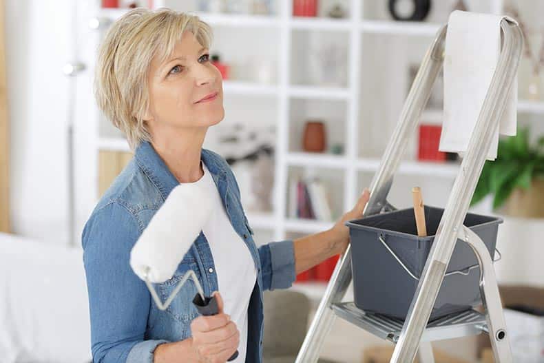 A 55+ woman holding a paint roller.