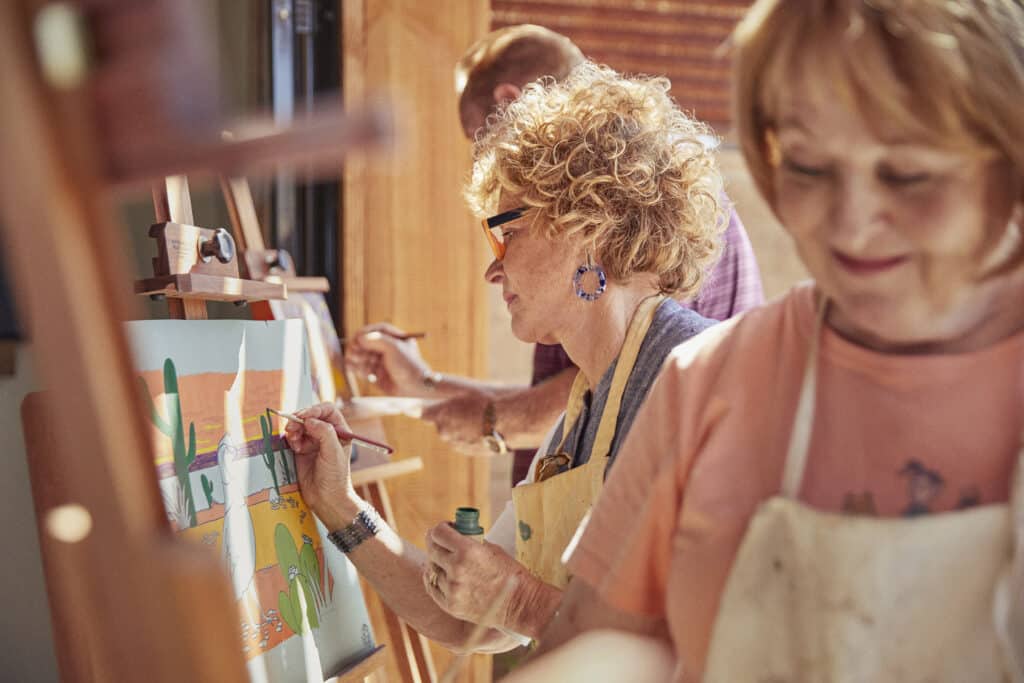 A group of active adults taking an art class in their 55+ community.