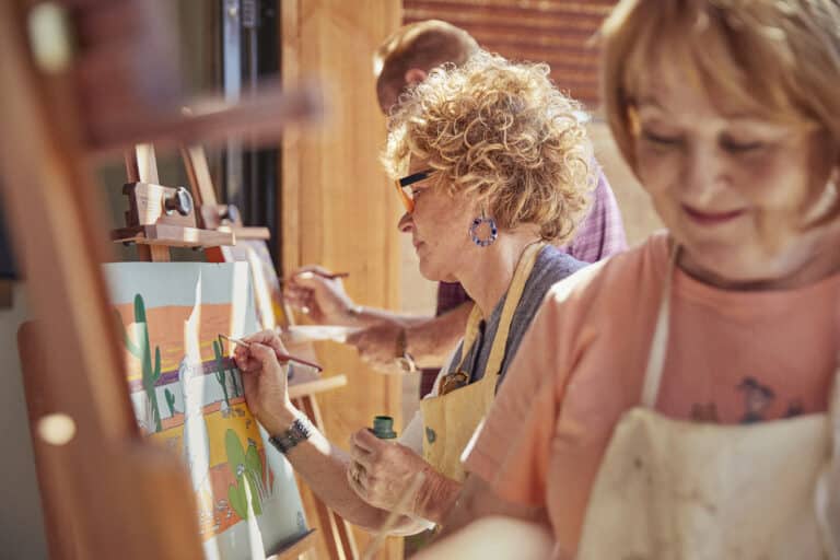 A group of active adults taking an art class in their 55+ community.