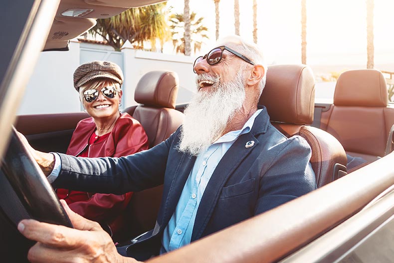 A happy senior couple having fun driving in a convertible car.