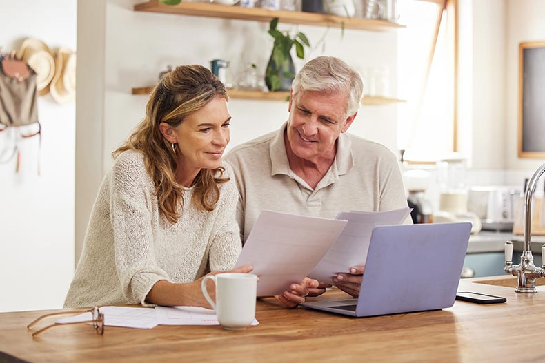 A 55+ couple checking financial documents to finalize their new home purchase.