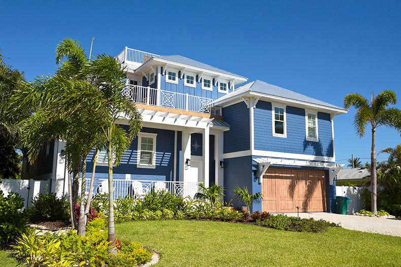 A new Florida house with palm trees and landscaping near the beach.