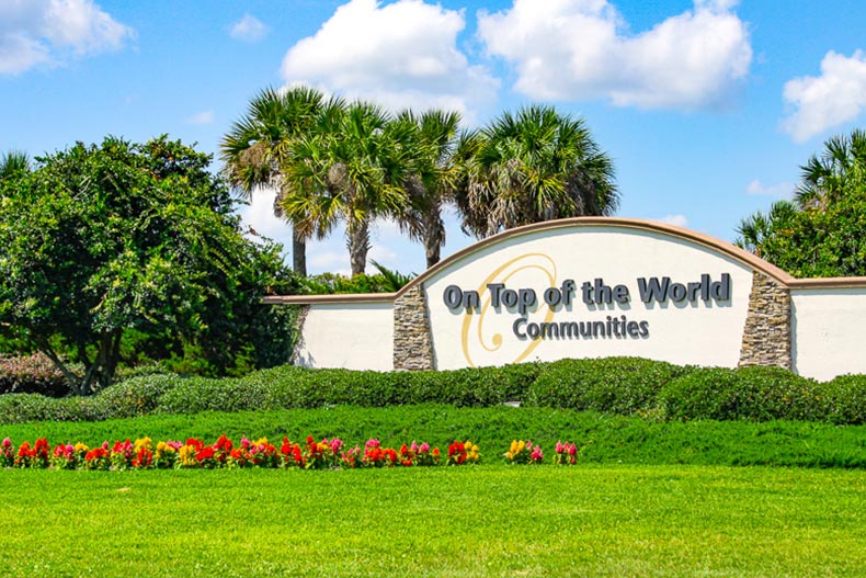 Palm trees and greenery surrounding the community sign for On Top of the World in Ocala, Florida.