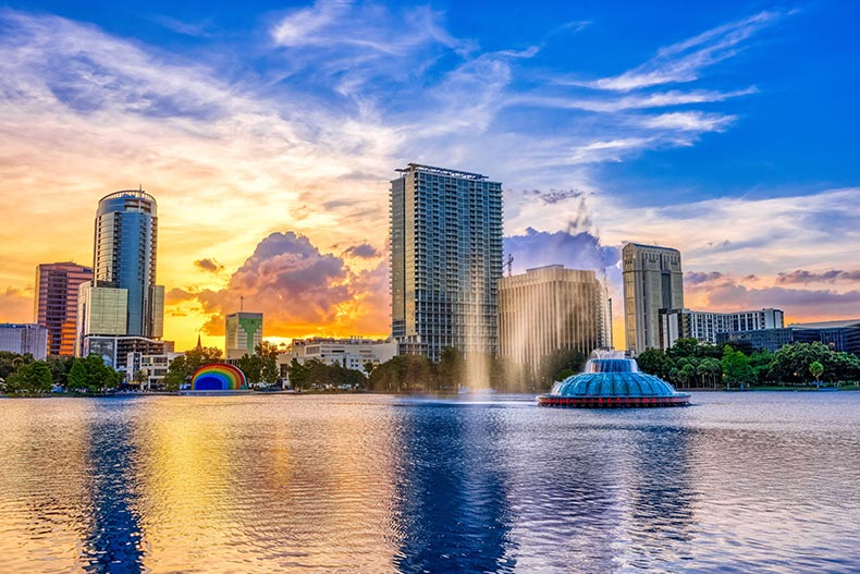 Sunset and clouds over the Orlando skyline and fountain at Lake Eola Park.