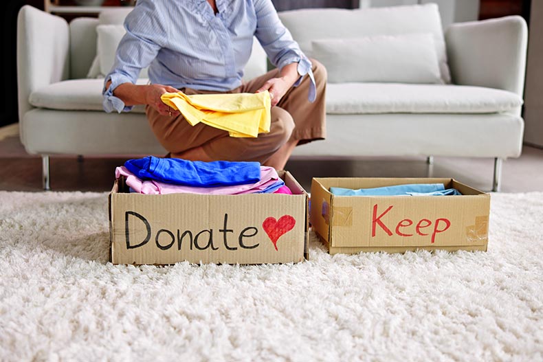 A 55+ woman donating, decluttering, and cleaning up old clothes.