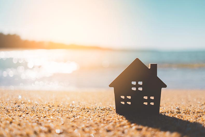 Small home model on a sunset beach with sand in the background.