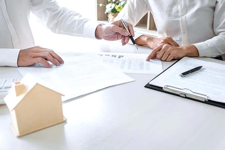 A real estate broker agent presenting a customer with an insurance form agreement.