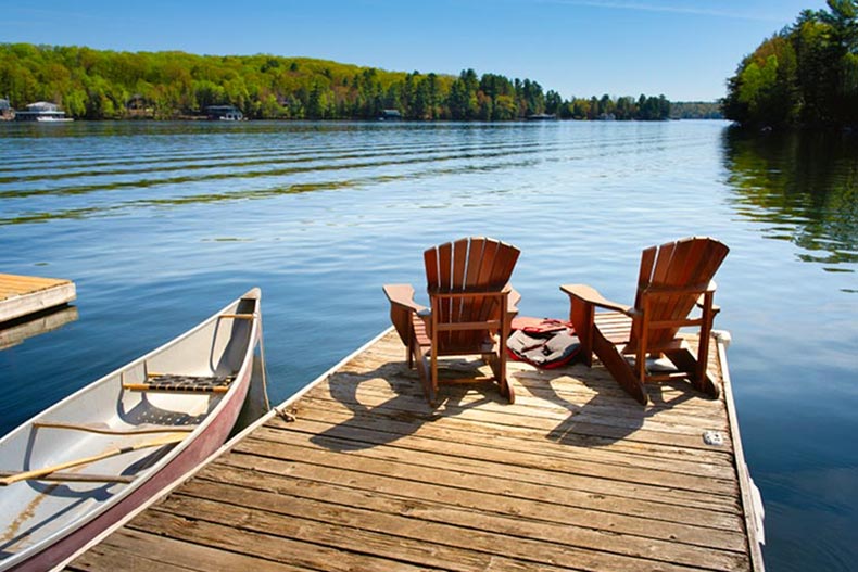 Lounge chairs on a dock on a peaceful lake.