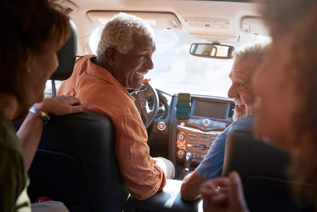 A group of 55+ friends driving in a car together.