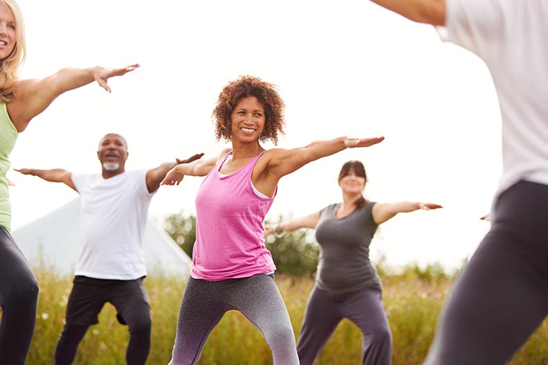 A group of 55+ men and women at an outdoor yoga retreat.