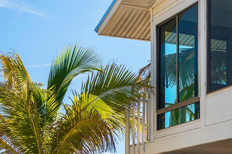 Corner of a wooden beach house by tall palm tree under a blue sky in Central Florida.
