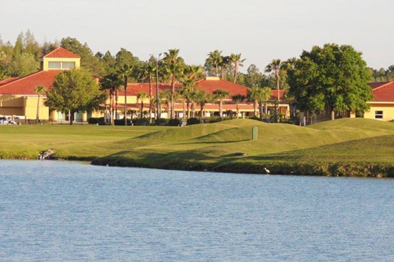 View across the water of palm trees surrounding a community building on the grounds of Cypress Lakes in Lakeland, Florida.