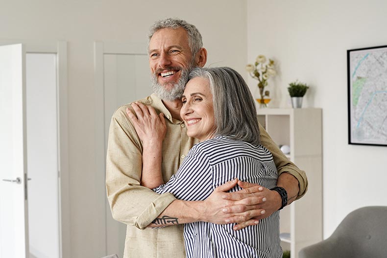 A carefree 55+ couple embracing after buying a new house.