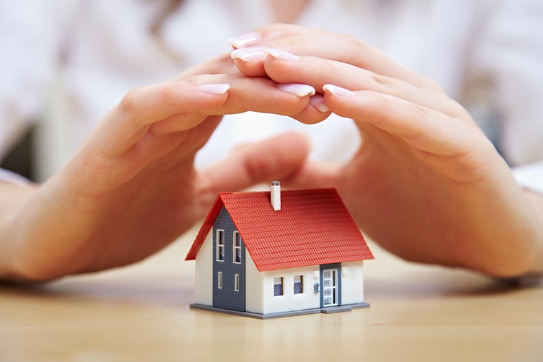 Female hands hovering over a small model house.