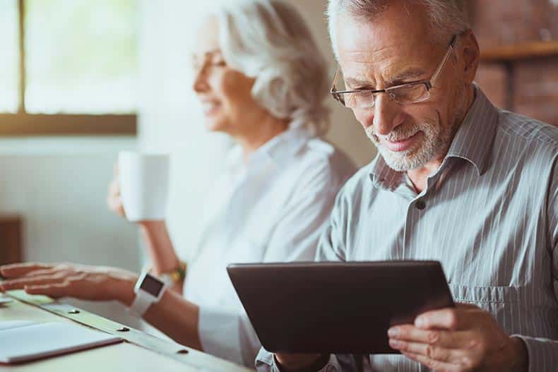 A 55+ man looking at home insurance discounts on a tablet.